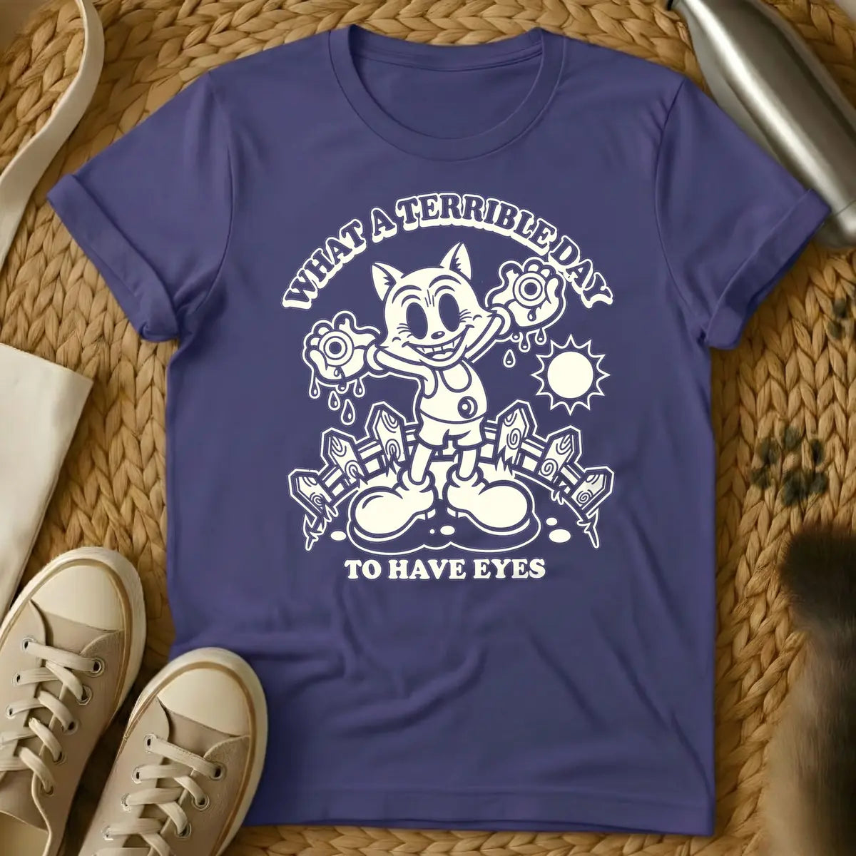 Purple - Cream retro cartoon character, resembling a grinning cat with large eyes, holding two dripping eyeballs in its hands. Behind it are a picket fence and a bright sun. Arched text above reads "WHAT A TERRIBLE DAY" and straight text below reads "TO HAVE EYES".