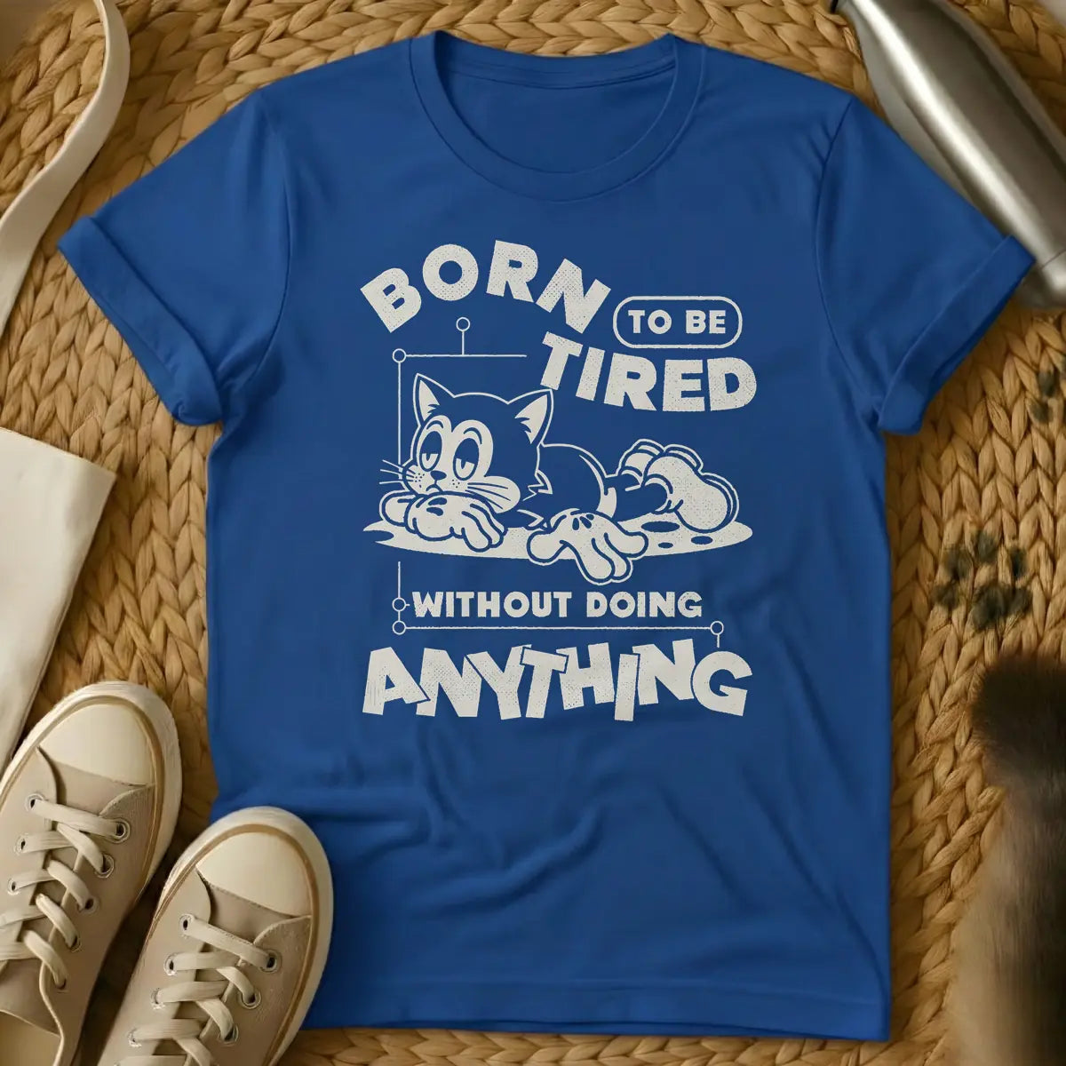 Royal - Distressed cream t-shirt design featuring a tired-looking cartoon cat lying down and the text 'BORN TO BE TIRED WITHOUT DOING ANYTHING'.