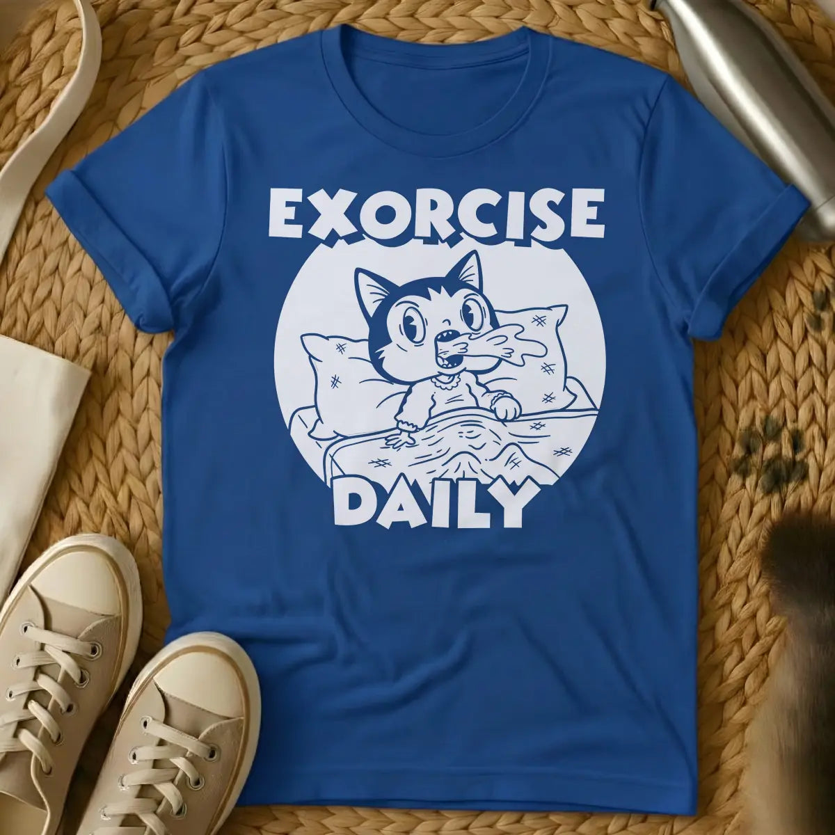 Royal - T-shirt design of a cartoon cat sleeping comfortably under a blanket with a pillow. Above the cat is the word 'EXORCISE' and below is 'DAILY'.