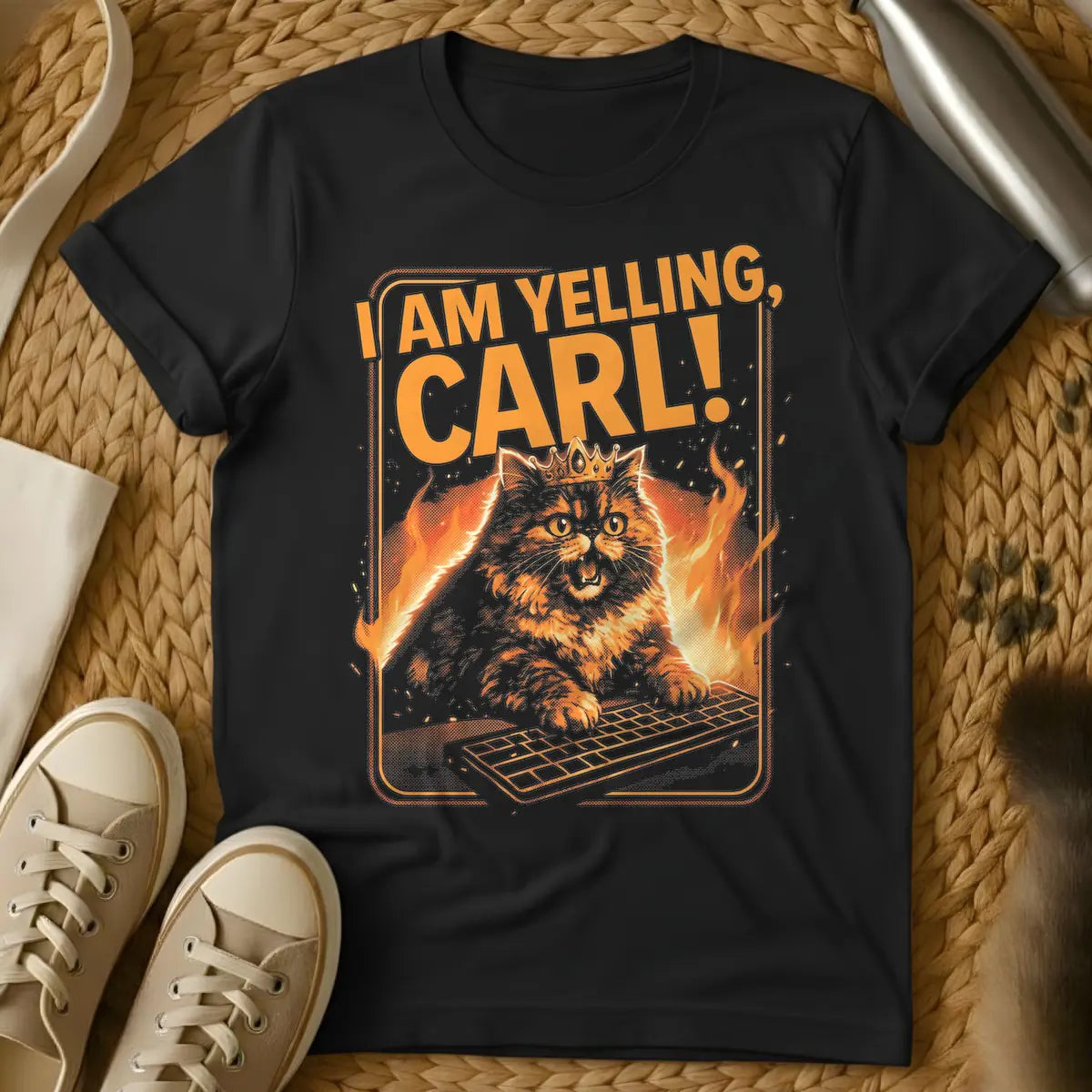 Black - Orange and black t-shirt design featuring a crowned, angry-looking cat with wide eyes and an open mouth, surrounded by flames, aggressively typing on a computer keyboard. Above the cat, the bold orange text reads "I AM YELLING, CARL!"