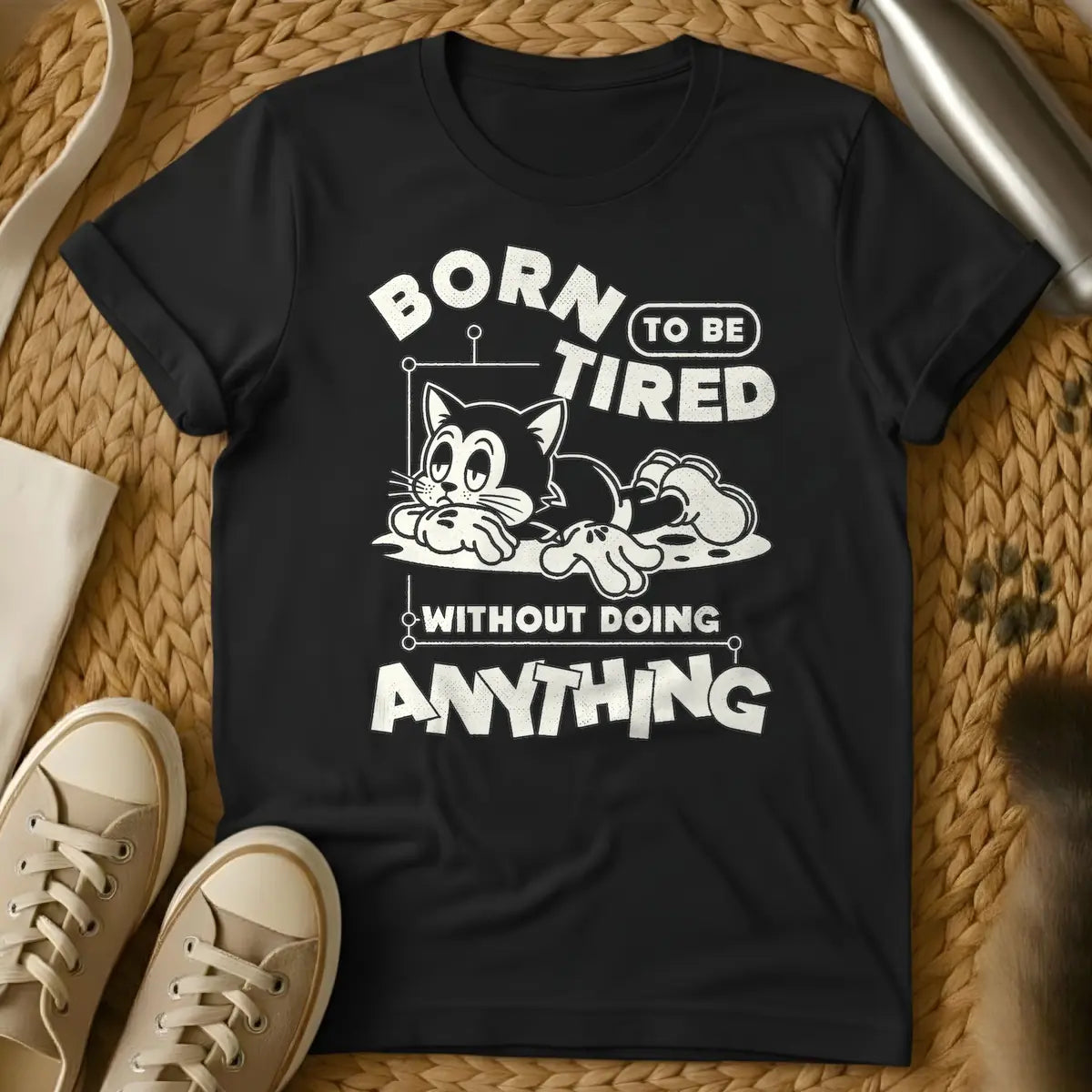 Black - Distressed cream t-shirt design featuring a tired-looking cartoon cat lying down and the text 'BORN TO BE TIRED WITHOUT DOING ANYTHING'.