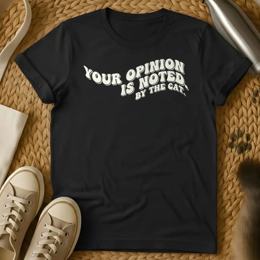 Black - T-shirt design featuring the phrase "YOUR OPINION IS NOTED BY THE CAT." in a cream, bubbly retro font.