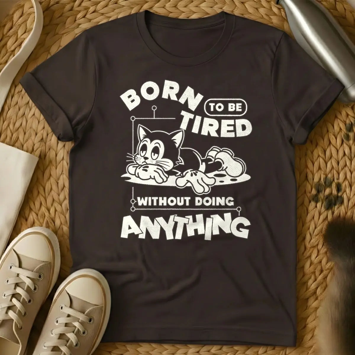 Dark Chocolate - Distressed cream t-shirt design featuring a tired-looking cartoon cat lying down and the text 'BORN TO BE TIRED WITHOUT DOING ANYTHING'.