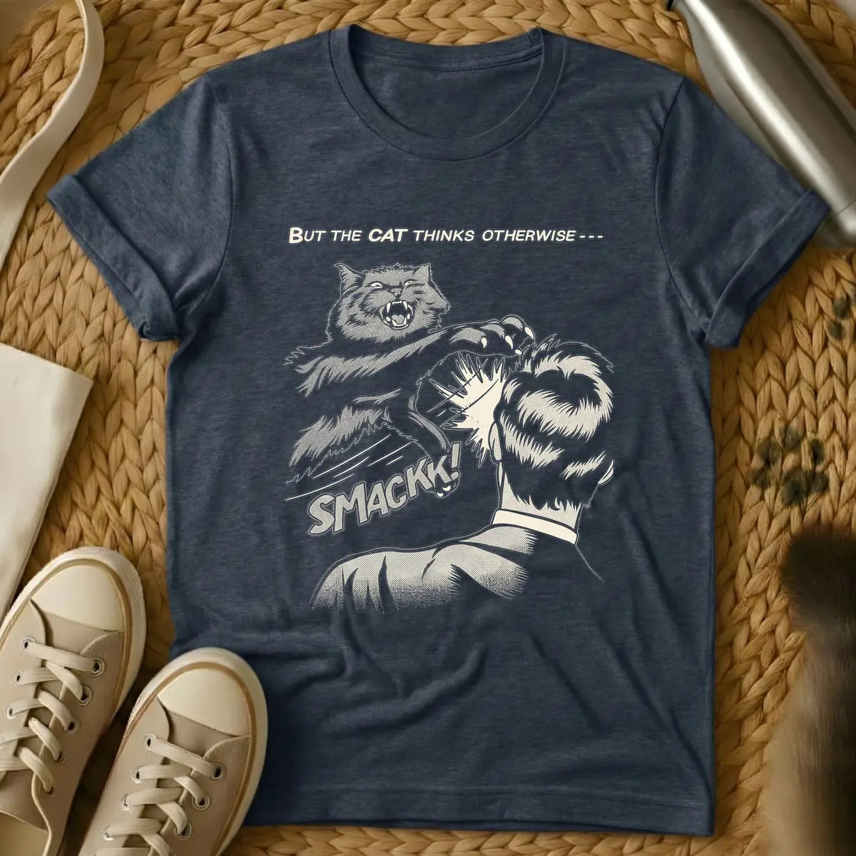 Heather Navy - Vintage comic book style illustration in beige tones with halftone shading. An angry cat with sharp claws is mid-air, slapping the back of a person's head. Below the action, the word 'SMACKK!' appears in a bold comic font. Above the scene, the text reads 'BUT THE CAT THINKS OTHERWISE ---'.