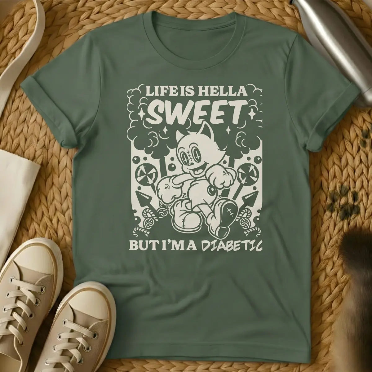 Military Green - Monochrome t-shirt design featuring a cheerful, running vintage cartoon cat amidst clouds, stars, lollipops, and candy canes. Above the cat, the text reads 'LIFE IS HELLA SWEET' in a bold, curvy font, with 'SWEET' being prominent. Below the cat, 'BUT I'M A DIABETIC' is written in a contrasting, handwritten style.