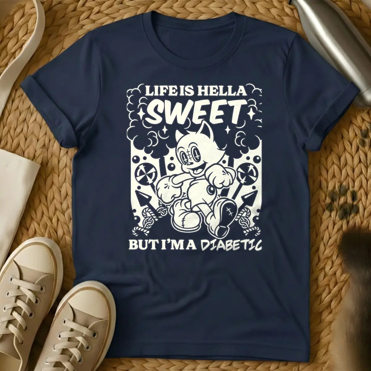 Navy - Monochrome t-shirt design featuring a cheerful, running vintage cartoon cat amidst clouds, stars, lollipops, and candy canes. Above the cat, the text reads 'LIFE IS HELLA SWEET' in a bold, curvy font, with 'SWEET' being prominent. Below the cat, 'BUT I'M A DIABETIC' is written in a contrasting, handwritten style.