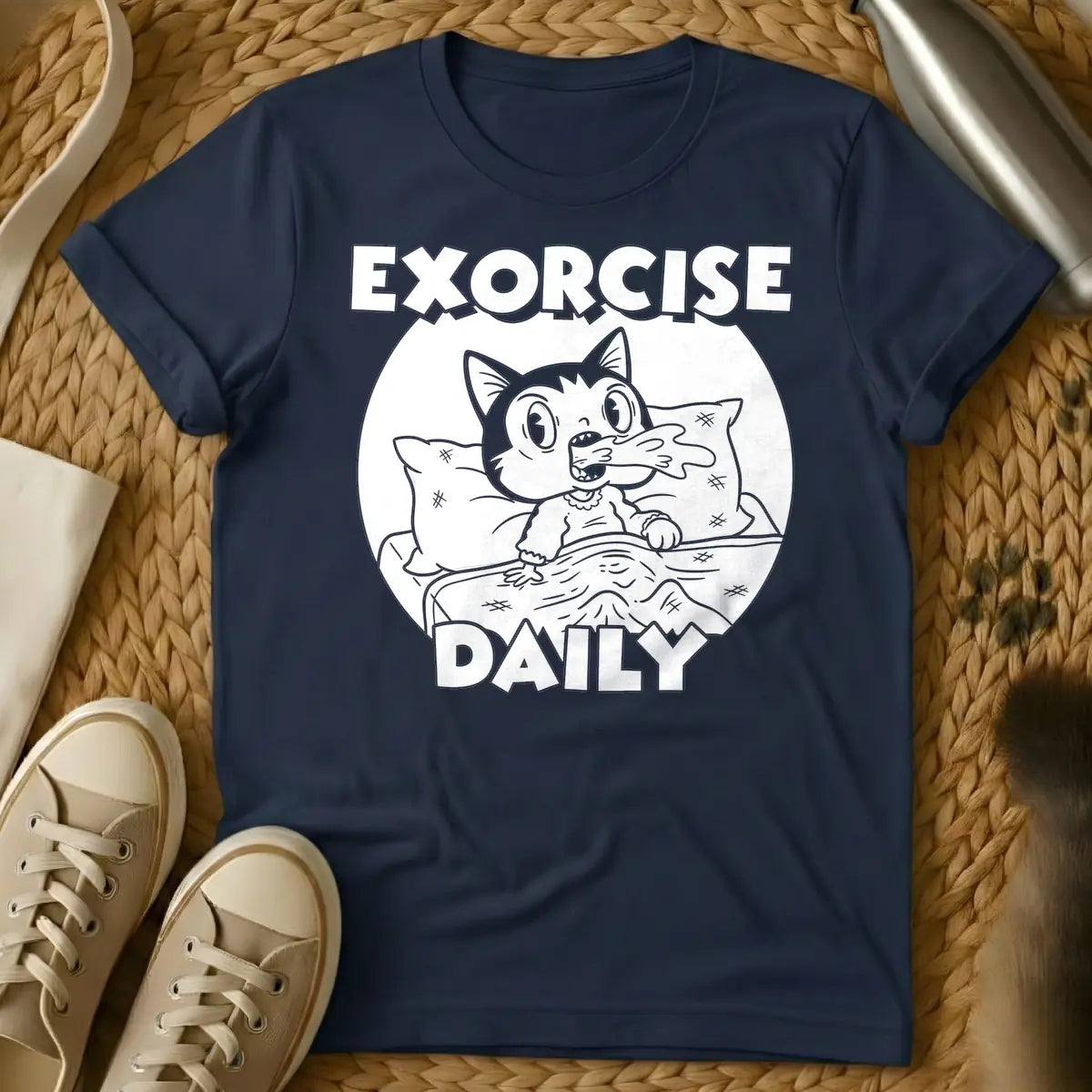 Navy - T-shirt design of a cartoon cat sleeping comfortably under a blanket with a pillow. Above the cat is the word 'EXORCISE' and below is 'DAILY'.