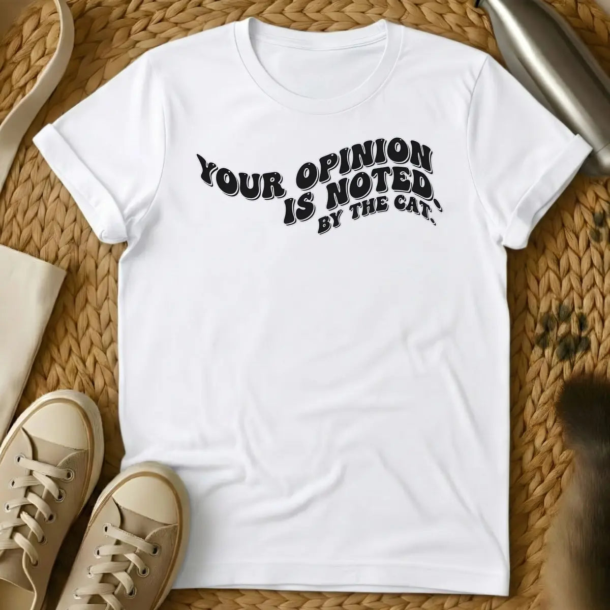 White - T-shirt design featuring the phrase "YOUR OPINION IS NOTED BY THE CAT." in a cream, bubbly retro font.
