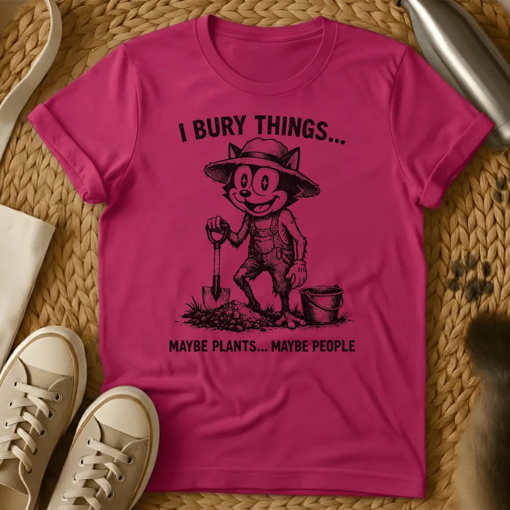 Heliconia - Vintage-style graphic tee featuring a grinning cat character in gardening clothes holding a shovel with text "I bury things... maybe plants... maybe p