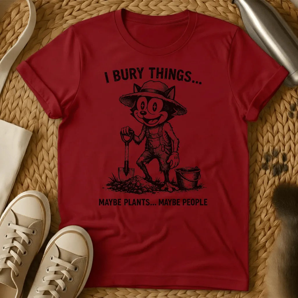 Red - Vintage-style graphic tee featuring a grinning cat character in gardening clothes holding a shovel with text "I bury things... maybe plants... maybe p