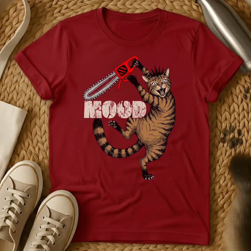 Red - Cartoon cat holding red chainsaw with "MOOD" text on olive green t-shirt, displayed flat lay with sneakers