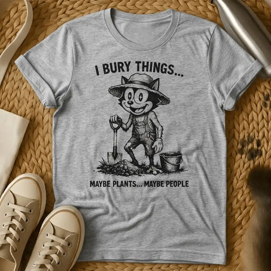 Sport Grey - Vintage-style graphic tee featuring a grinning cat character in gardening clothes holding a shovel with text "I bury things... maybe plants... maybe p